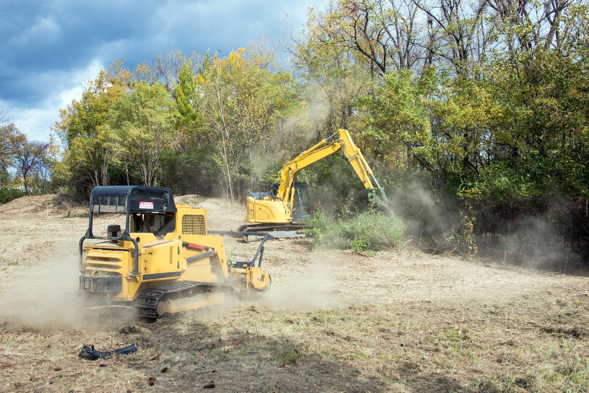 Forestry mulcher and backhoe machinery clearing parcel of land for development